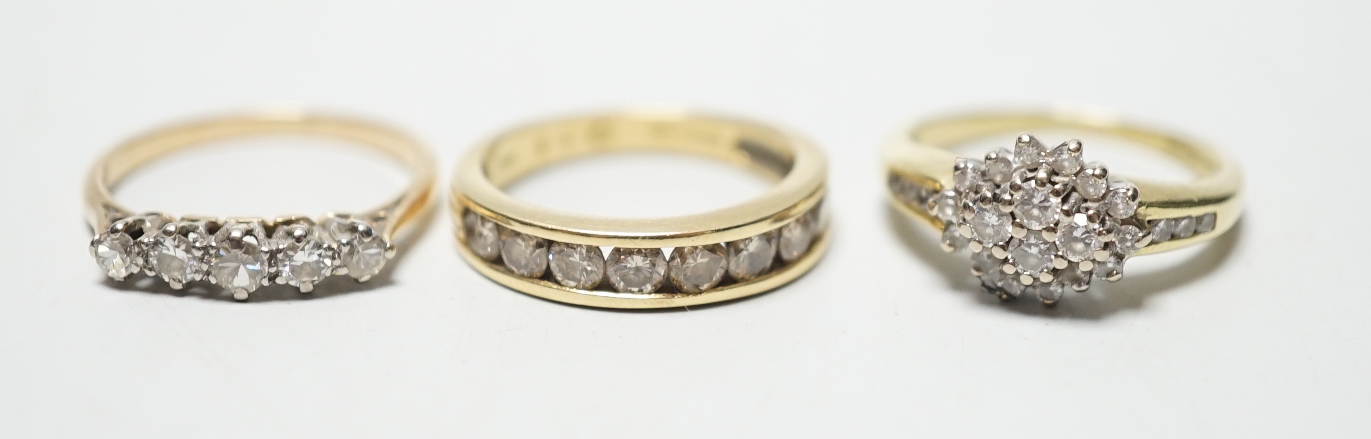 Two modern 18ct gold and diamond set rings, including nine stone channel set, size L and diamond cluster, size L and a yellow metal and five stone diamond set half hoop ring, size M, gross weight 9 grams.